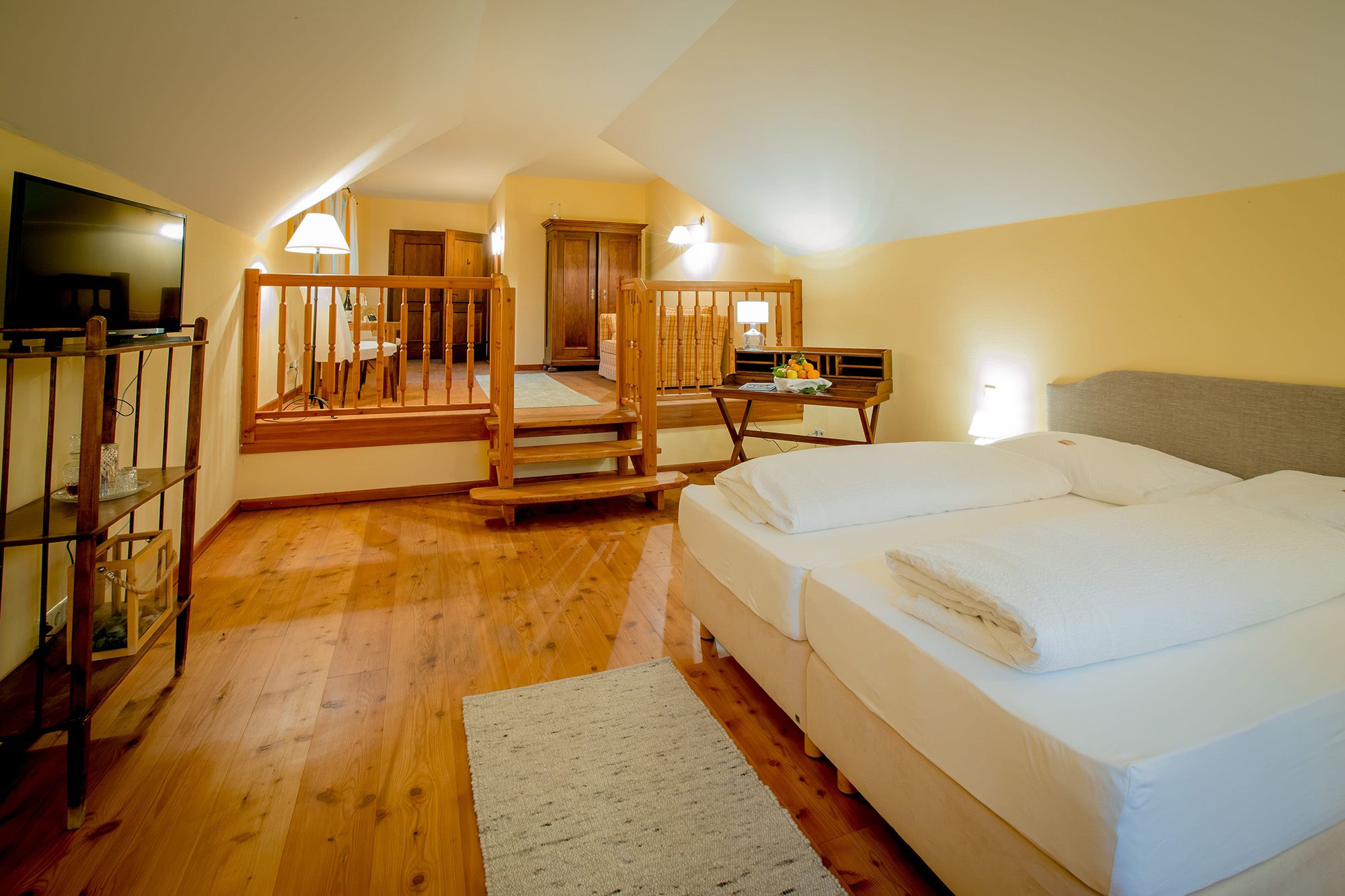 Ein gemütliches Hotelzimmer mit Doppelbett, Holzboden und einem kleinen Tisch mit Obst.