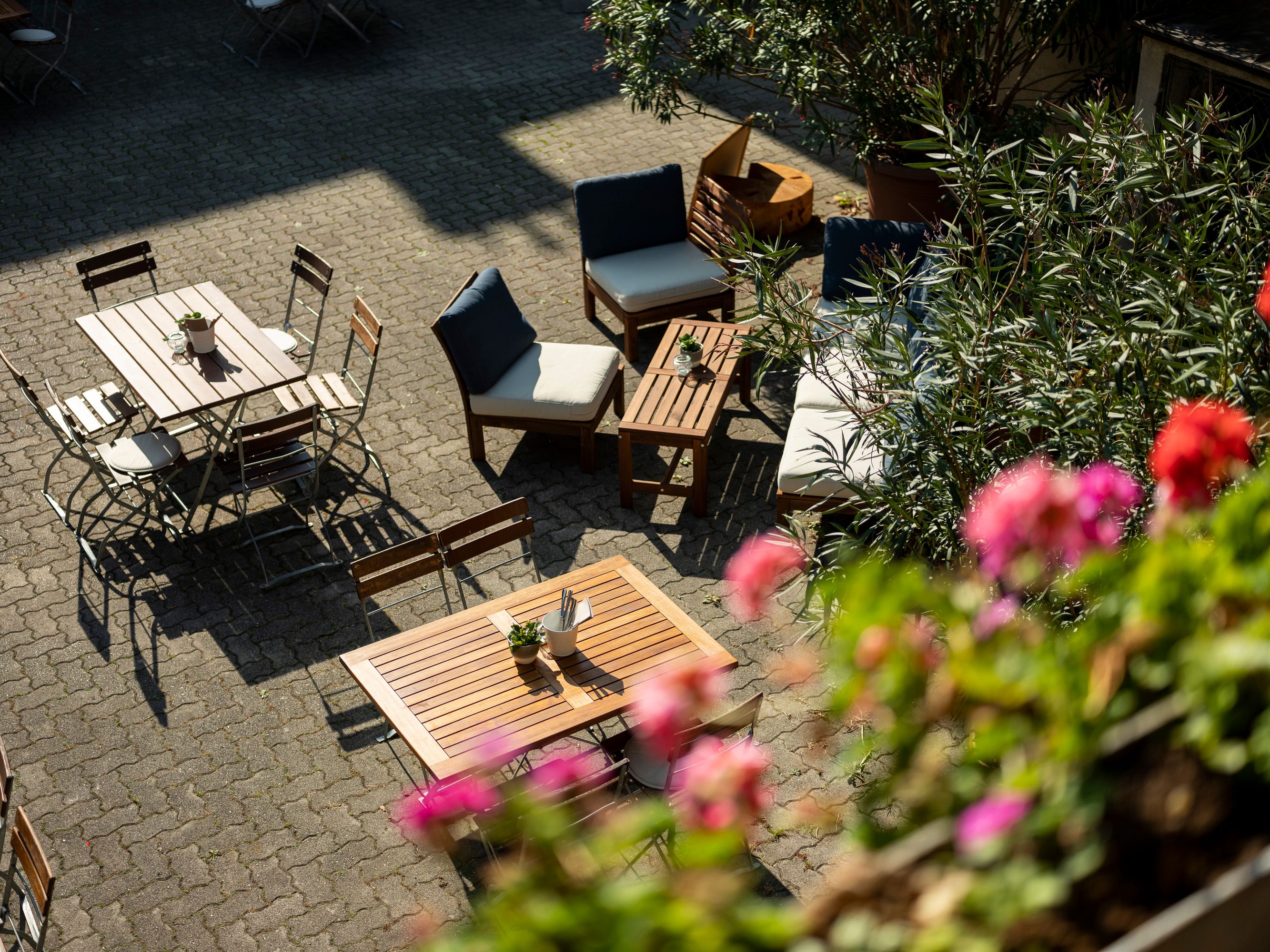Gemütlicher Innenhof mit Holzmöbeln und blühenden Pflanzen.