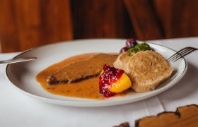 Ein Teller mit Hirschbraten, Knödeln, Preiselbeeren und Gemüse.