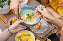 Eine Gruppe von Gästen teilt diverse Gerichte am Tisch im Gastgarten im Wirtshaus Beringer in Mank, darunter gefüllte selbstgemachte Pasta, Knödel und andere kleine Häppchen zum Teilen. 
