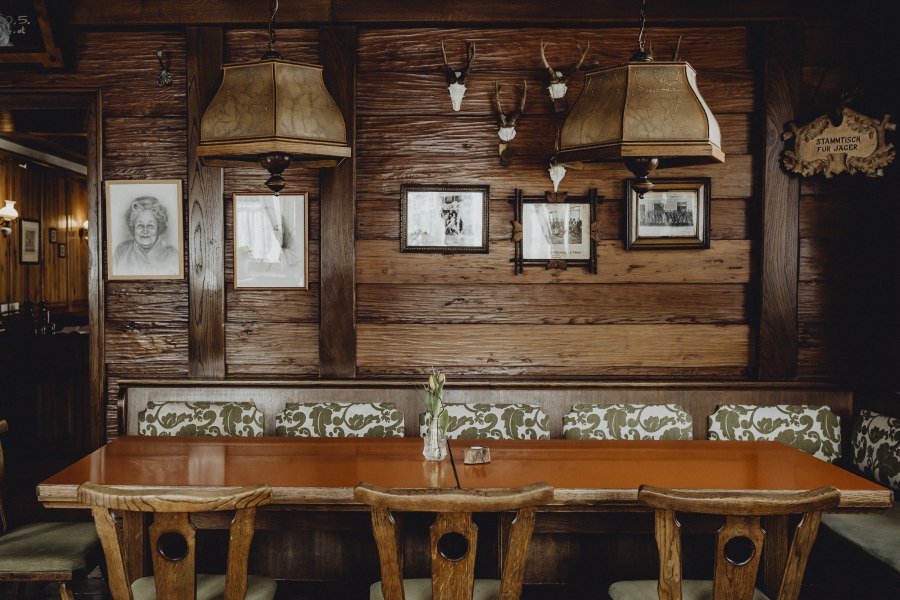 Gem&uuml;tliches Wirtshaus-St&uuml;berl mit Holztisch, St&uuml;hlen und rustikaler Dekoration an der Wand.