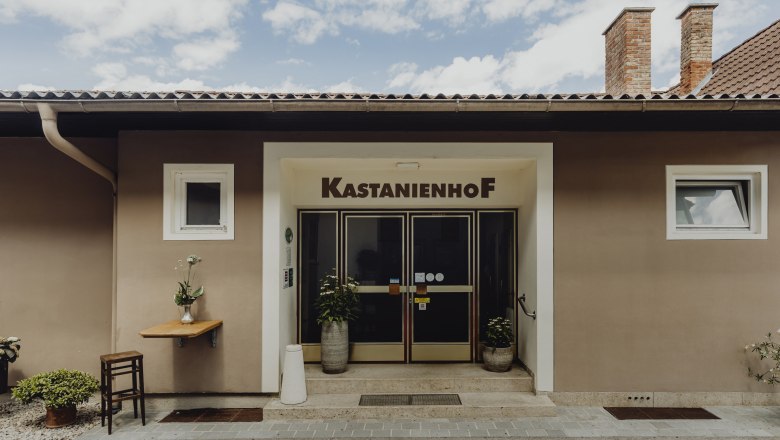 Eingang des Kastanienhofs in Grafenbach mit Pflanzen und Tisch.