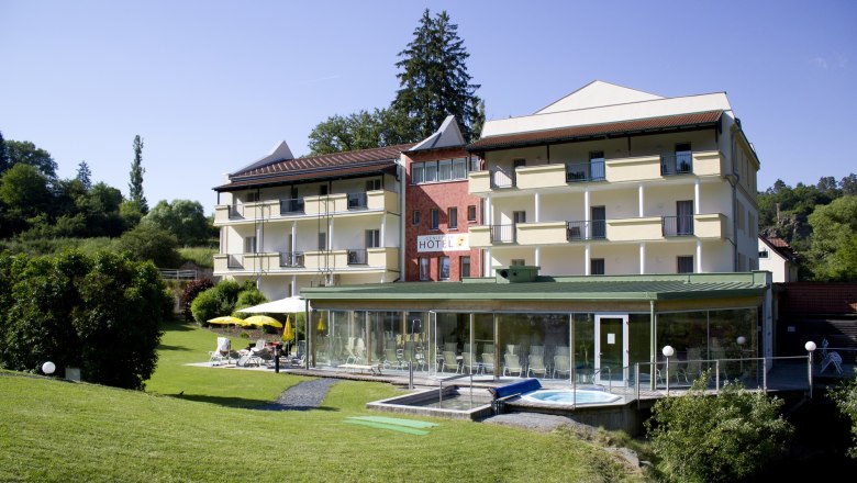 Au&szlig;enansicht eines Hotels mit Garten und Poolbereich.