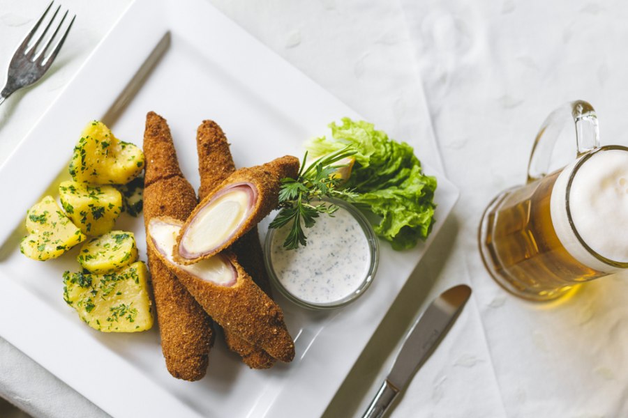 Gebackener Spargel mit Kartoffeln, Salat und Bier auf wei&szlig;em Teller.