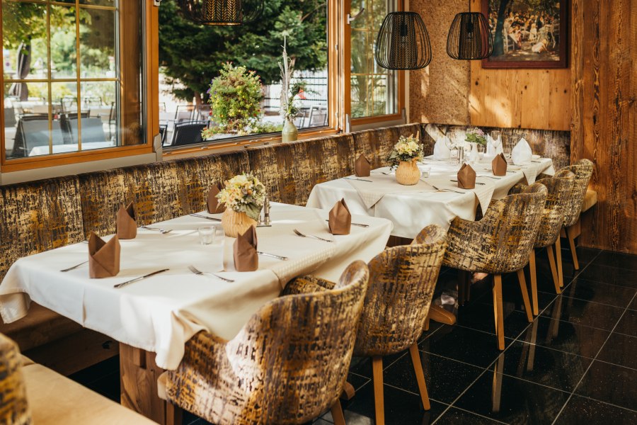Gem&uuml;tliches Restaurant mit gedeckten Tischen, Blumen und rustikalem Ambiente.