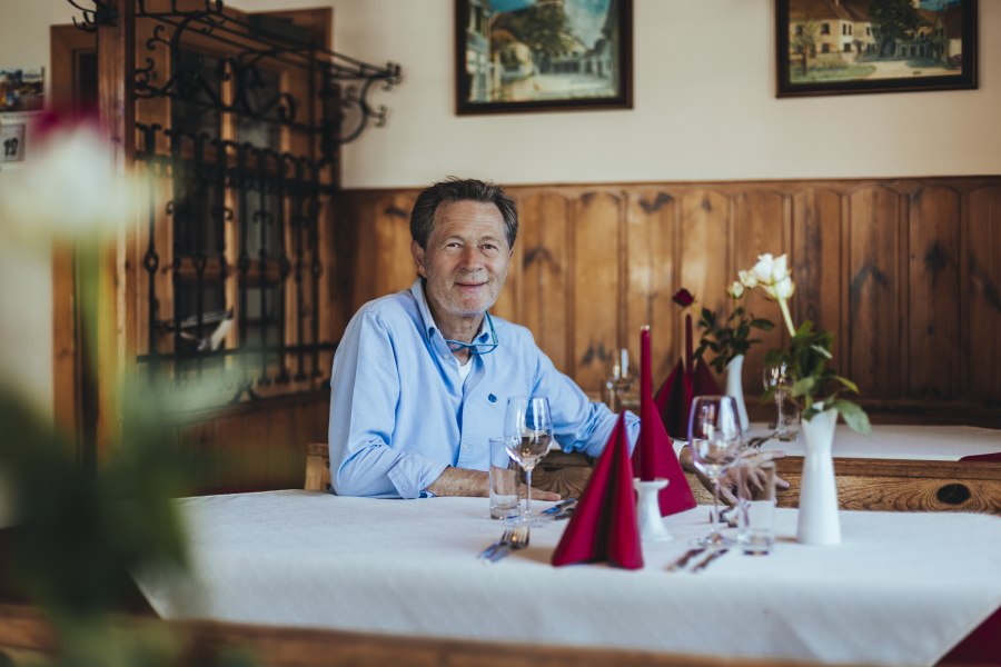 Karlheinz Ringl sitzt an einem gedeckten Tisch in seinem Gasthaus.