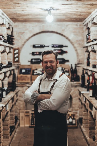 Ein Mann in einem Weinkeller mit Regalen voller Weinflaschen.