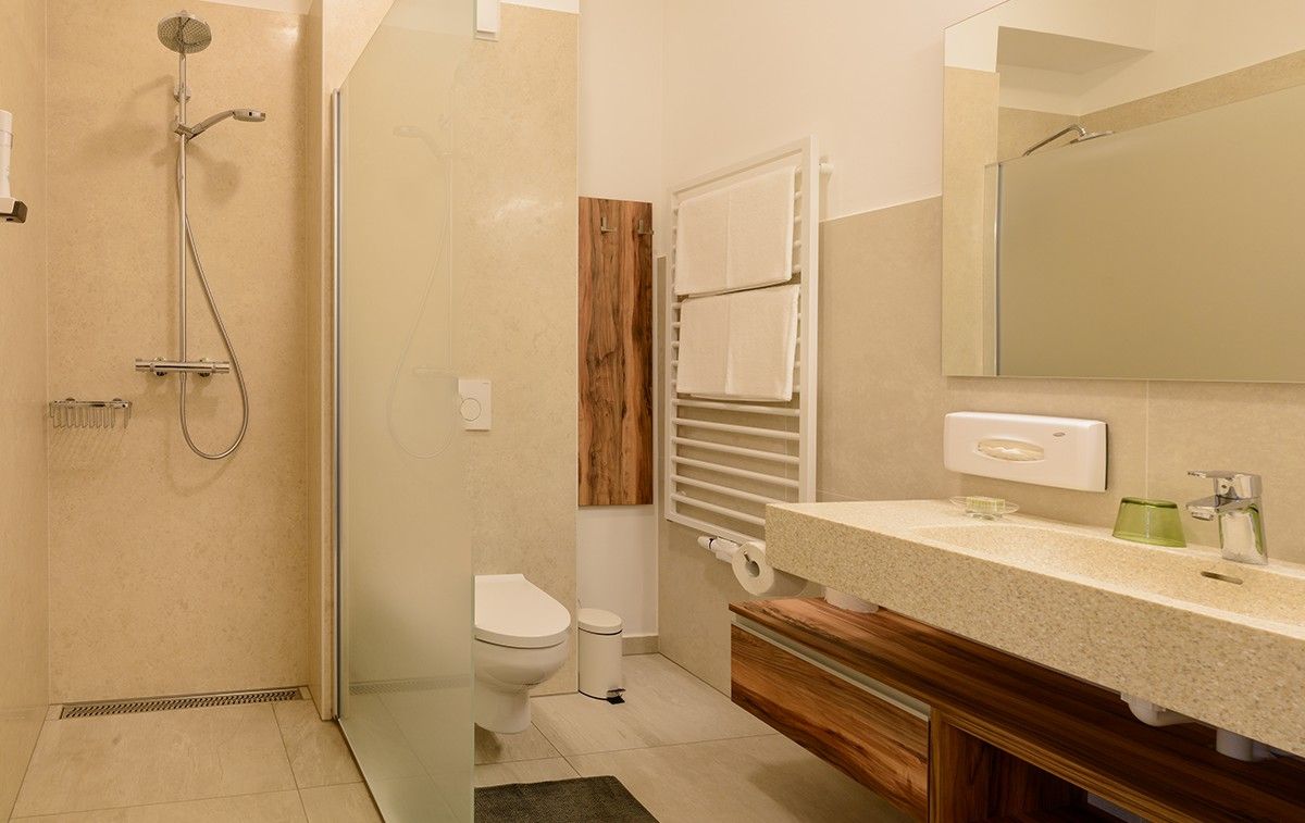 Modernes Badezimmer mit Dusche, WC, Waschbecken und Handtuchhalter.