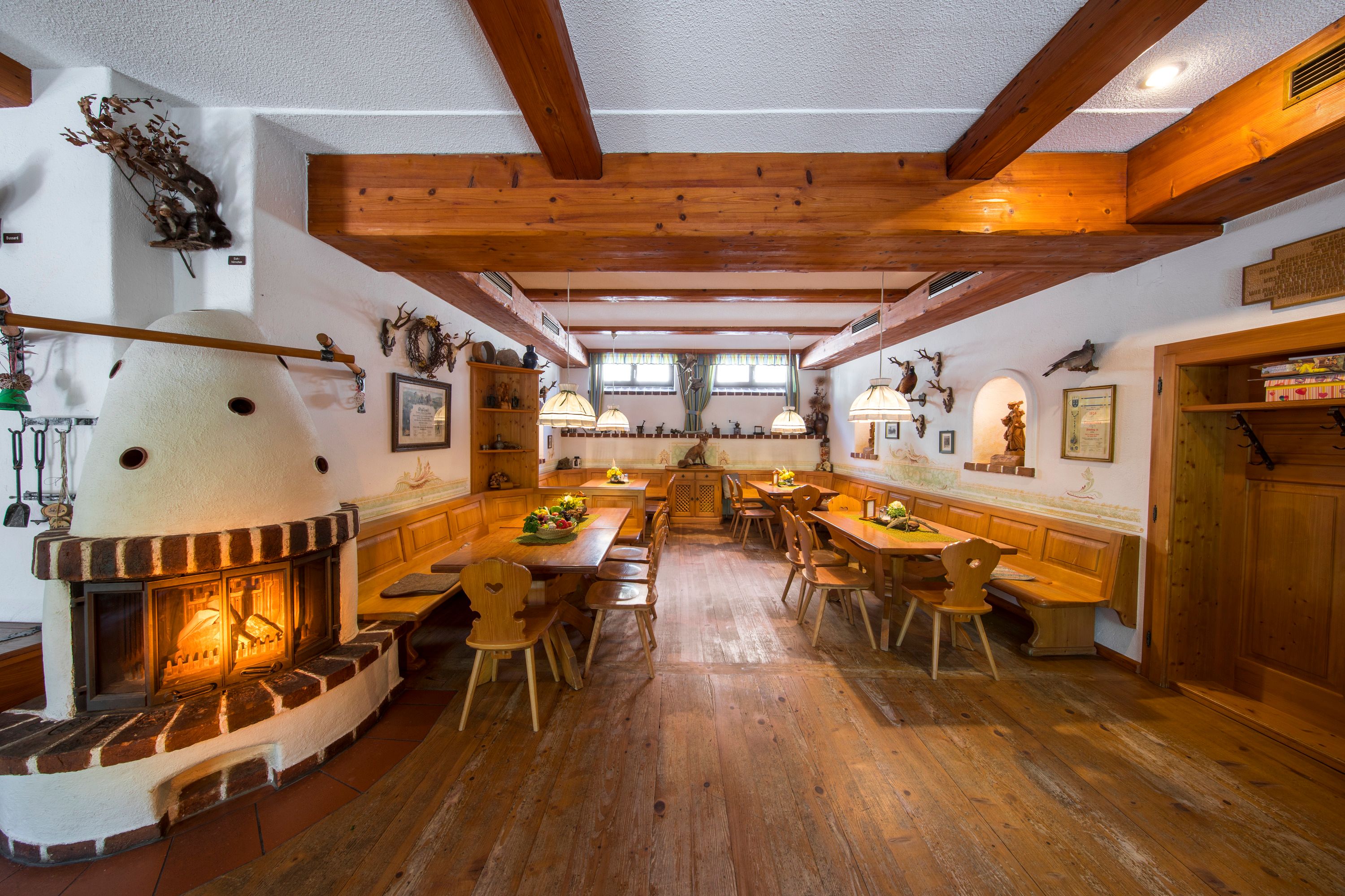 Gemütliche Gaststube mit Kamin, Holzmöbeln und rustikaler Dekoration.