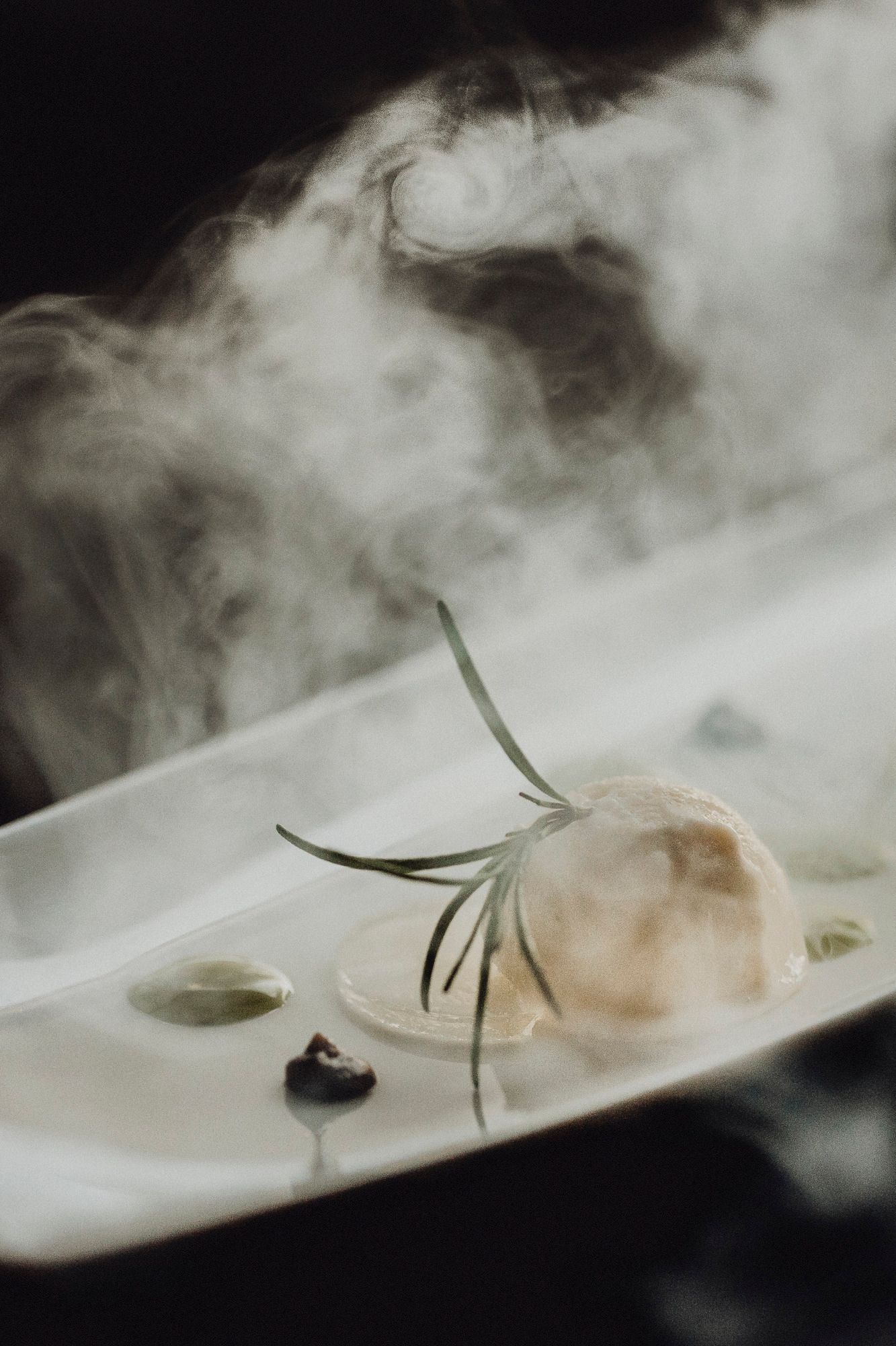 Ein Dessert mit Rosmarin und Rauch auf einem Teller.