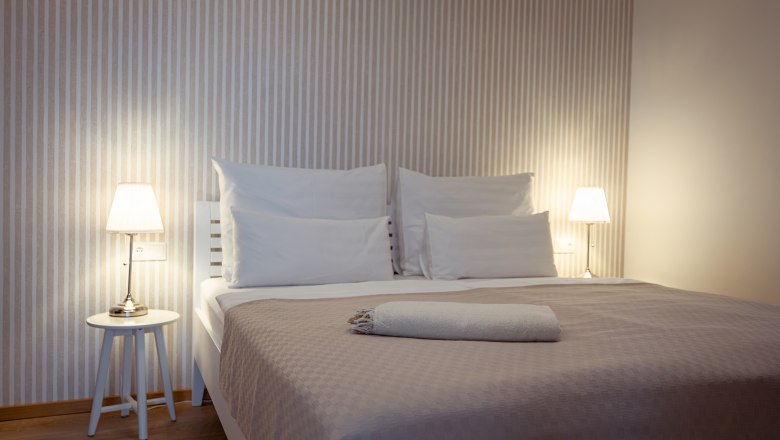 Modernes Schlafzimmer mit Doppelbett, Nachttischen und Lampen.