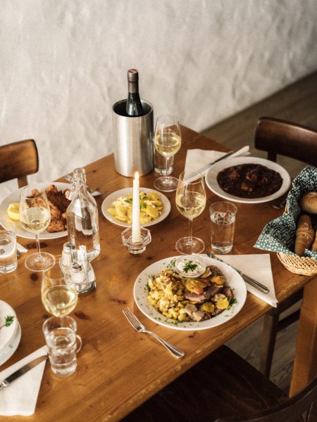 Gem&uuml;tlich gedeckter Tisch mit Wein, Kerze und traditionellen Gerichten.