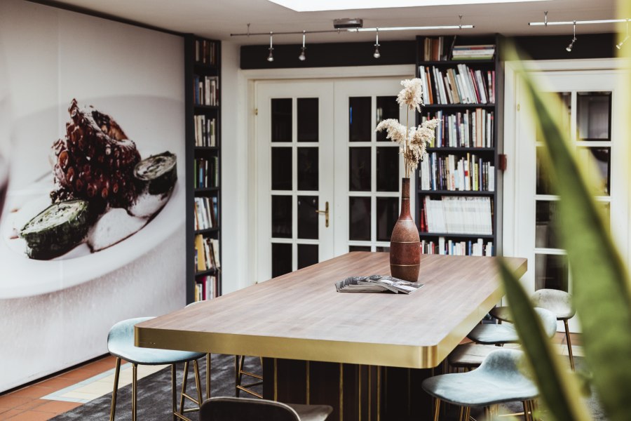 Moderner Raum mit großem Tisch, Bücherregalen und Wandbild.