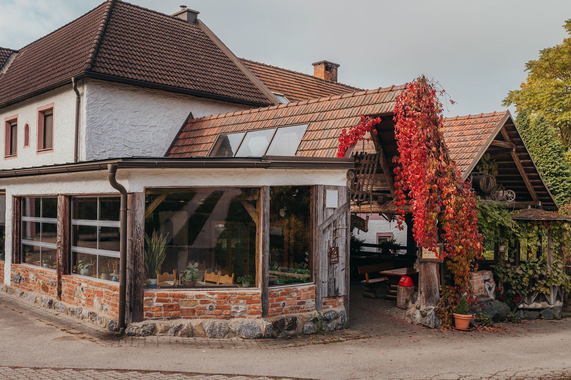 Umgeben von bunten Herbstblättern und der charmanten Architektur des Wirtshauses, lädt dieser Ort zum Verweilen ein. Die gemütliche Atmosphäre und die einladenden Farben der Natur schaffen eine perfekte Kulisse für einen entspannten Tag in den Bergen.