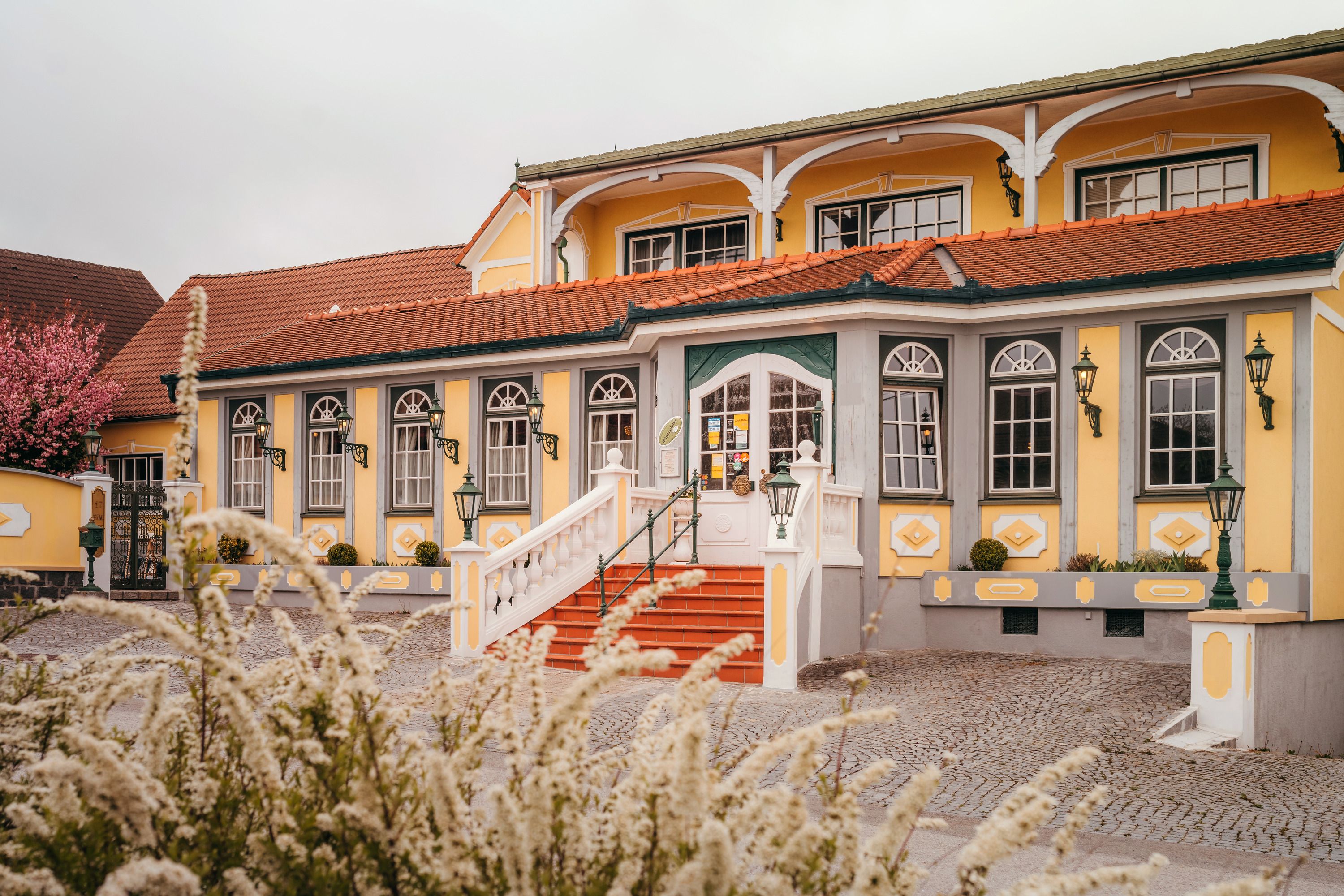 Ein gelber Landgasthof mit roten Dachziegeln und weißen Treppen in Vitis.
