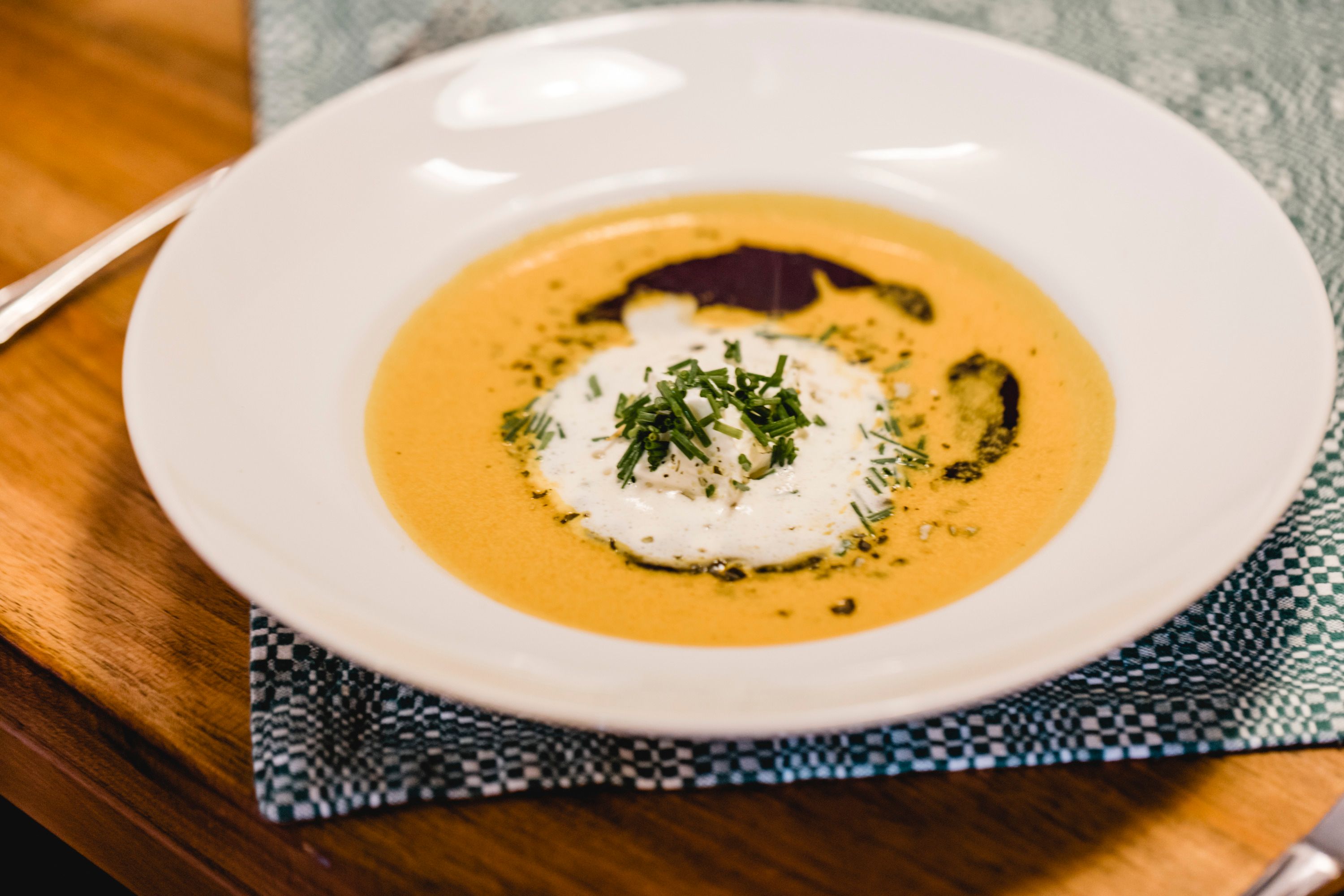 Ein Teller mit Kürbiscremesuppe, garniert mit Sahne und Kräutern.