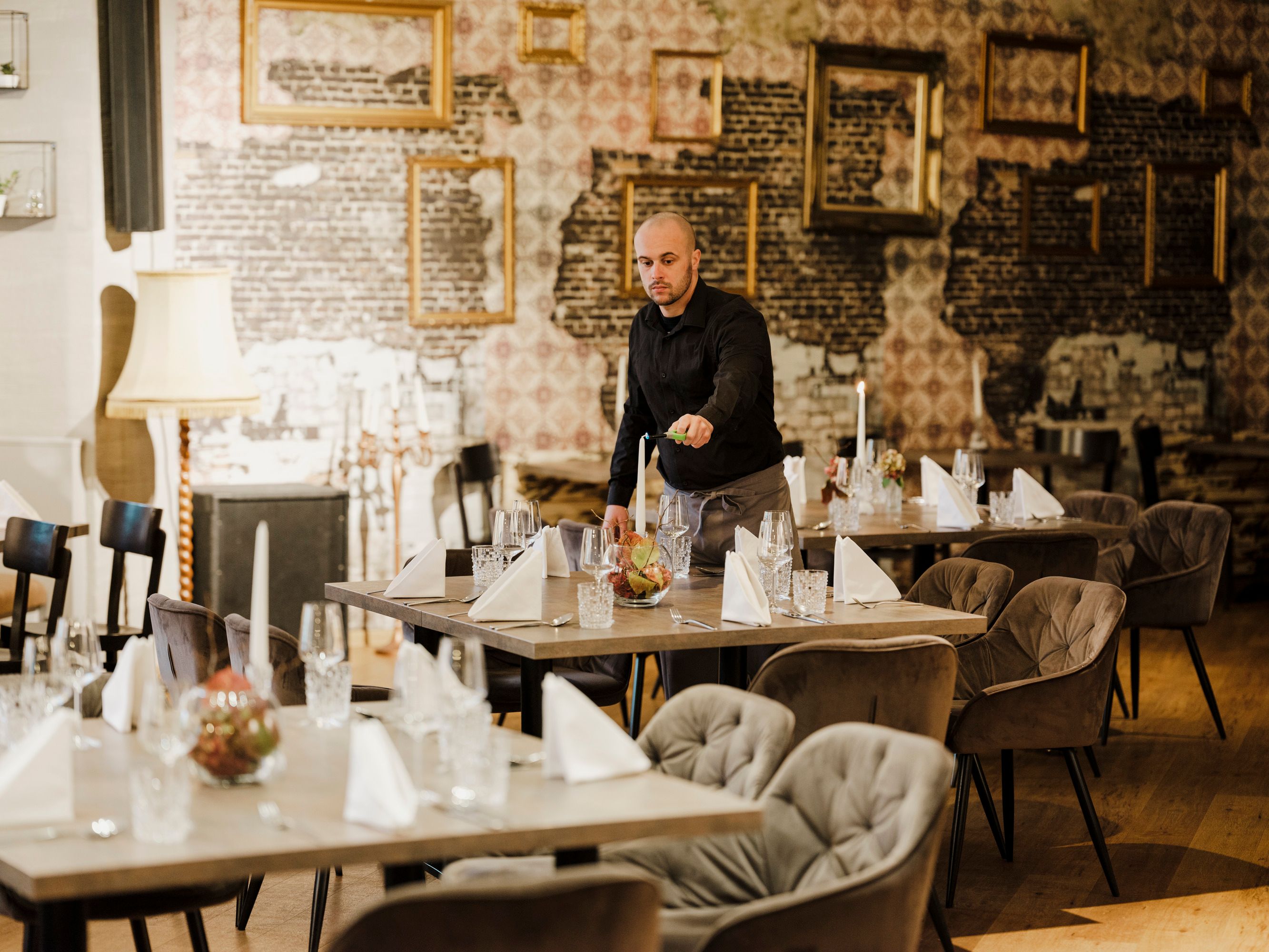 Kellner richtet Tische in stilvollem Restaurant mit Vintage-Dekor her.