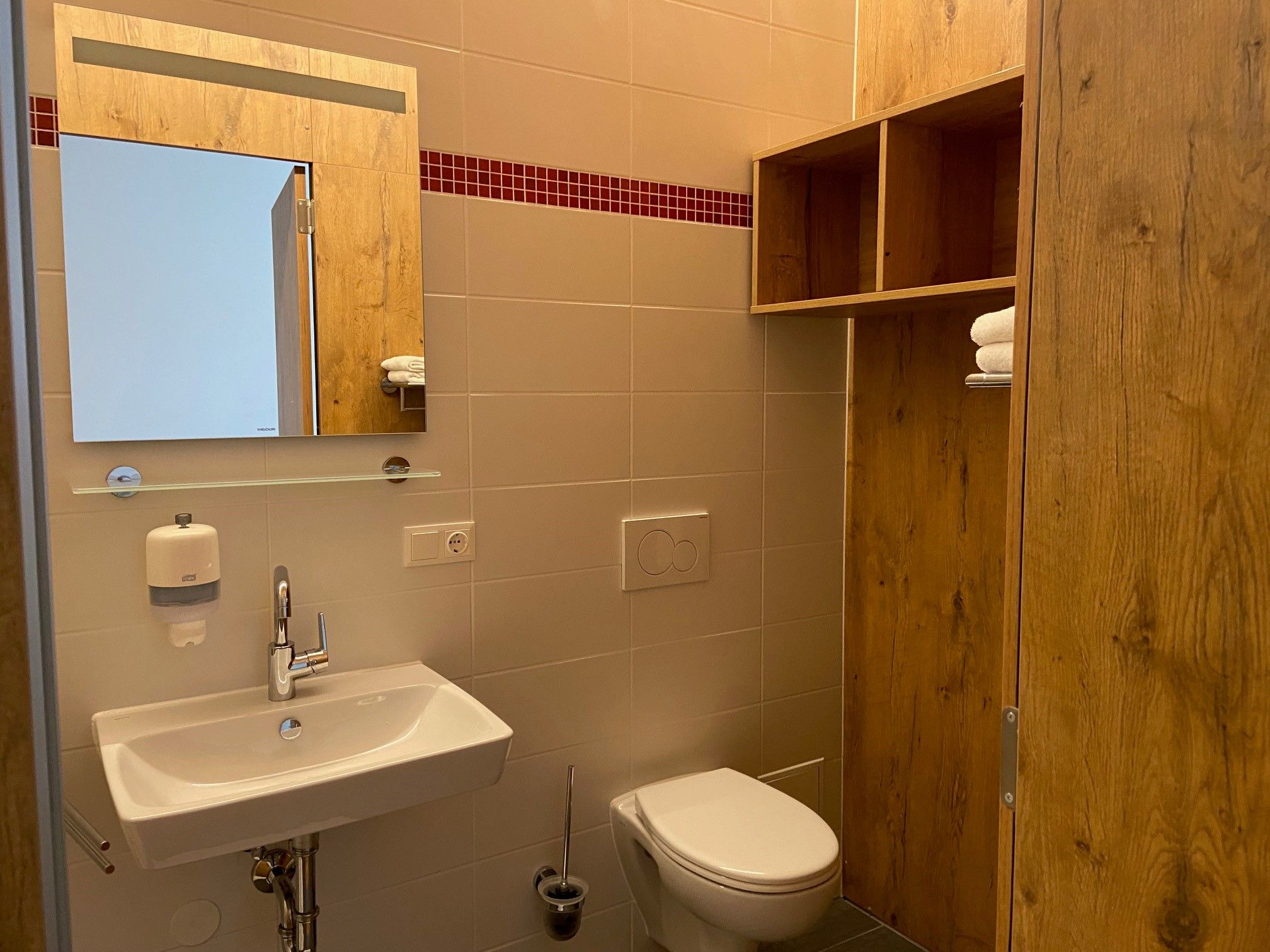 Modernes Badezimmer mit Waschbecken, Spiegel, WC und Holzregal.
