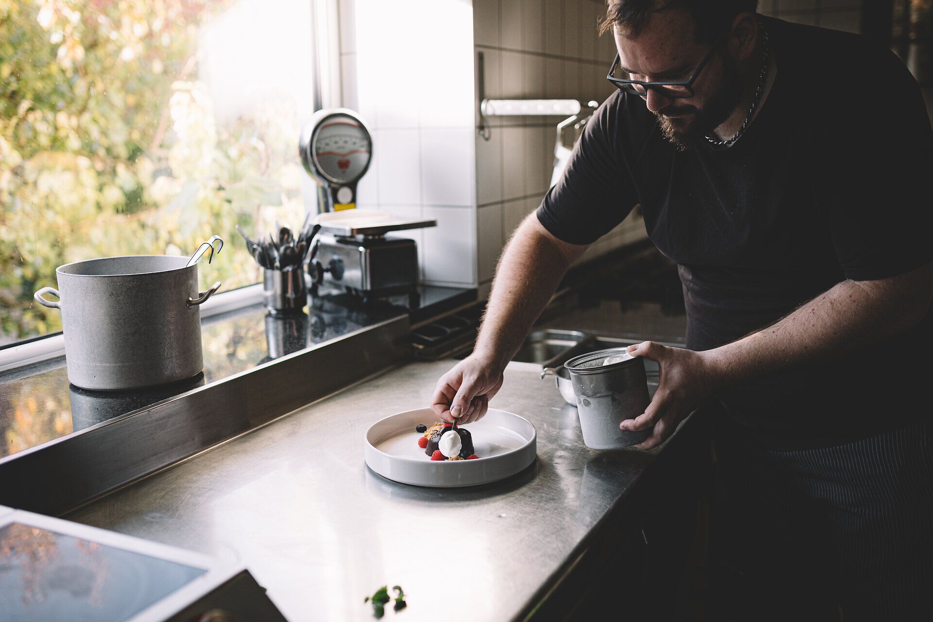 In der warmen Atmosphäre des Wirtshauses im Demutsgraben zaubert der Koch mit frischen Zutaten ein kunstvolles Gericht. Die bunten Früchte und die liebevolle Anrichtung versprechen ein Geschmackserlebnis, das die Sinne verführt. Hier wird die Tradition der Wirtshauskultur lebendig und lädt zum Verweilen ein.
