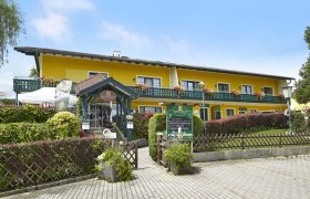 Gelbes Geb&auml;ude mit Balkon und Blumen, Krumbacherhof, Eingang mit Vordach und Schildern.