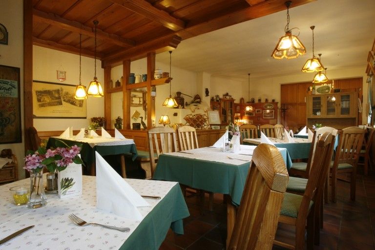 Innenansicht eines gemütlichen Wirtshauses mit Holzmöbeln und gedeckten Tischen.