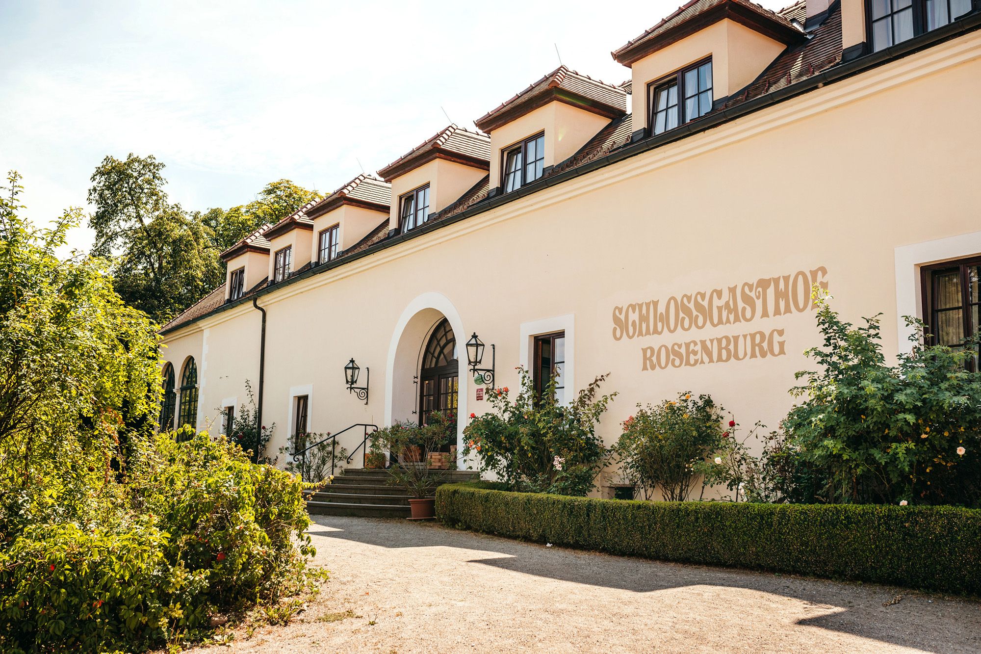 Außenansicht des Schlossgasthofs Rosenburg mit Garten und Eingangstreppe.