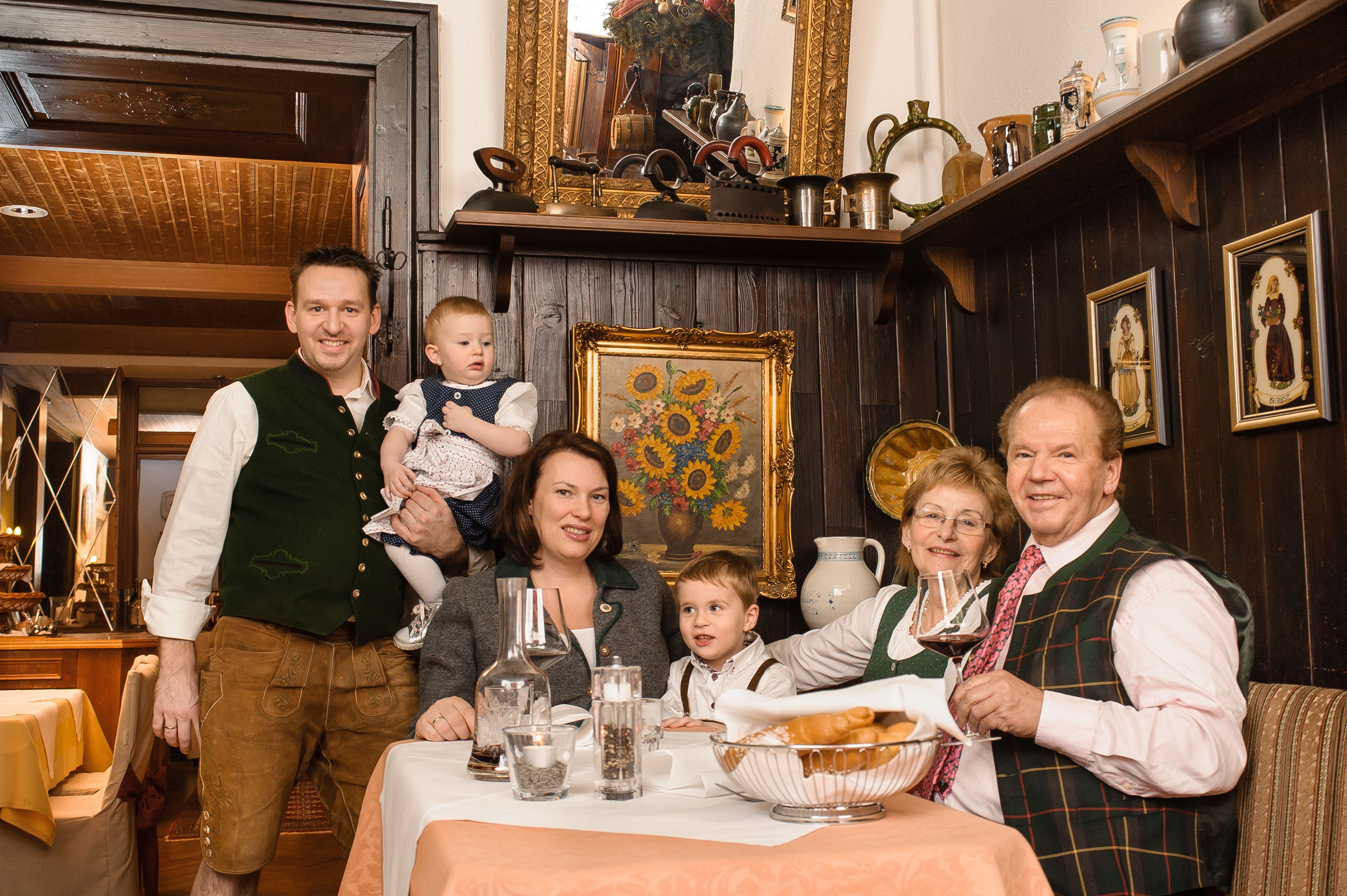 Eine Familie in traditioneller Kleidung sitzt an einem Tisch in einem rustikalen Restaurant.
