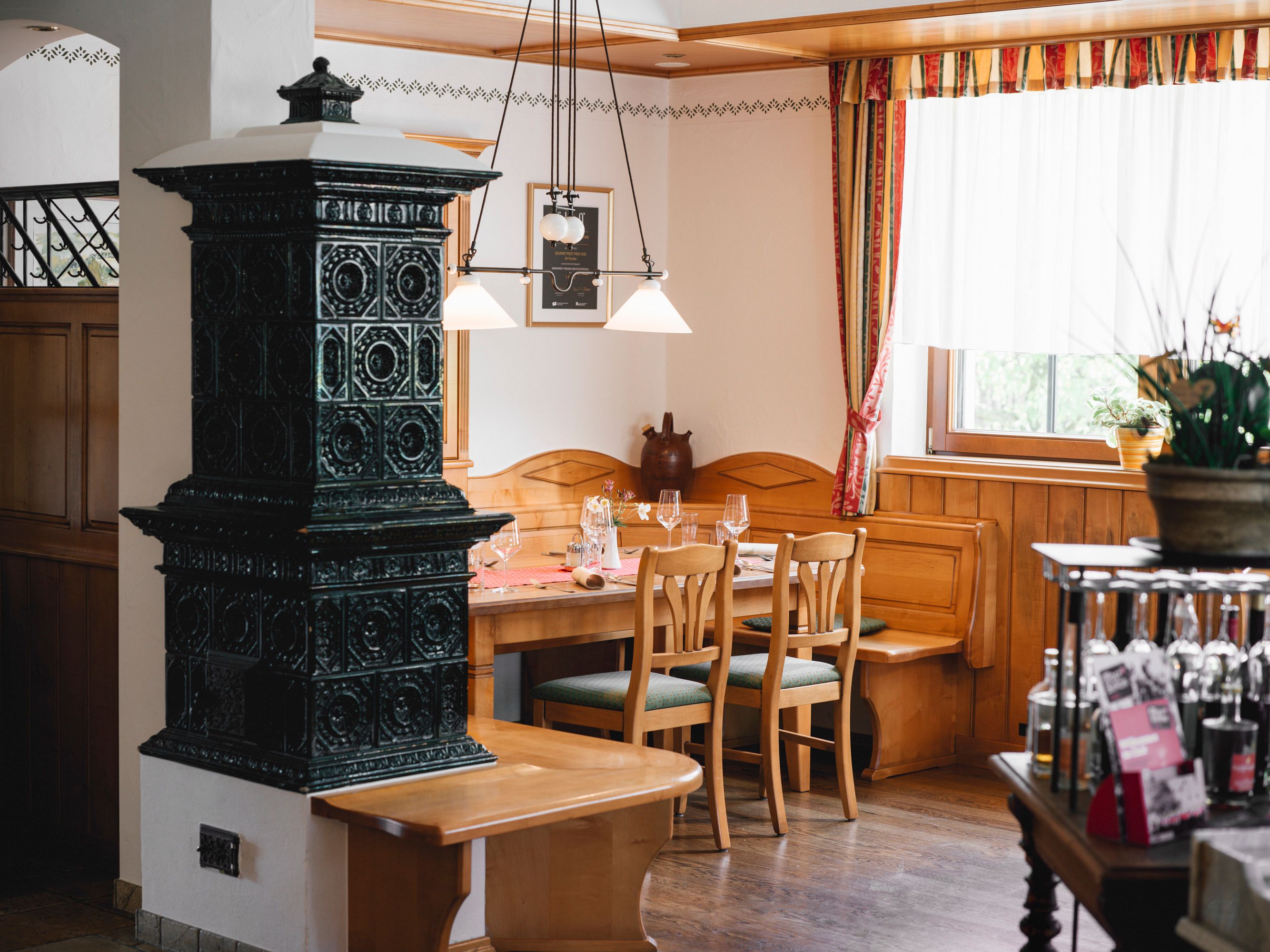 Gemütliche Wirtshausstube mit Holzmöbeln und Kachelofen.