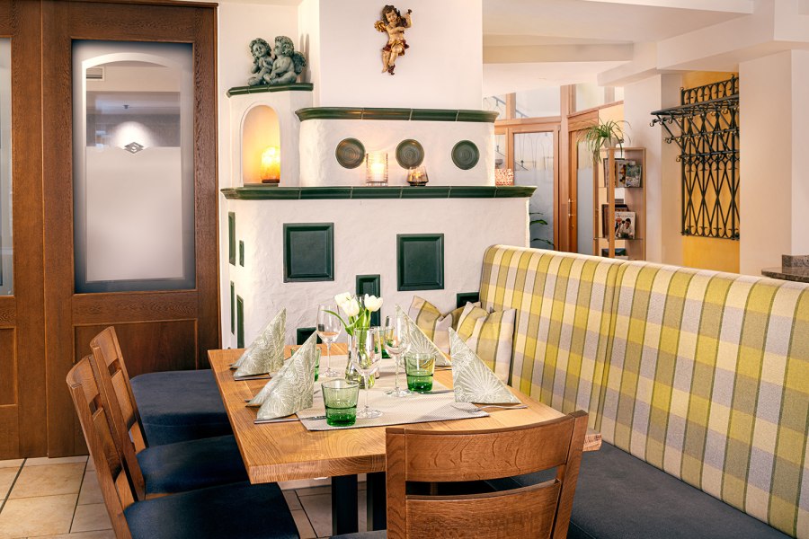 Gemütliches Restaurantinterieur mit Holztisch, Ofen und Dekoration.