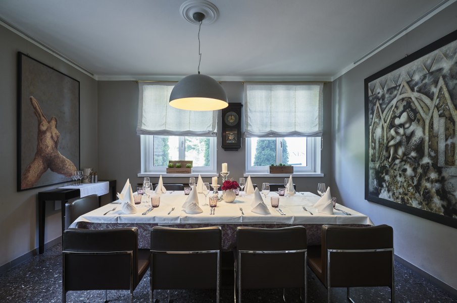 Elegantes Esszimmer mit gedecktem Tisch, Kunstwerken an den Wänden und großen Fenstern.