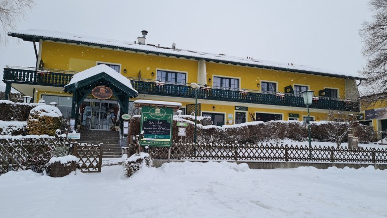 Krumbacherhof, © Wiener Alpen / Cornelia Schuh Gelbes Gebäude im Schnee mit grüner Veranda und Eingang.