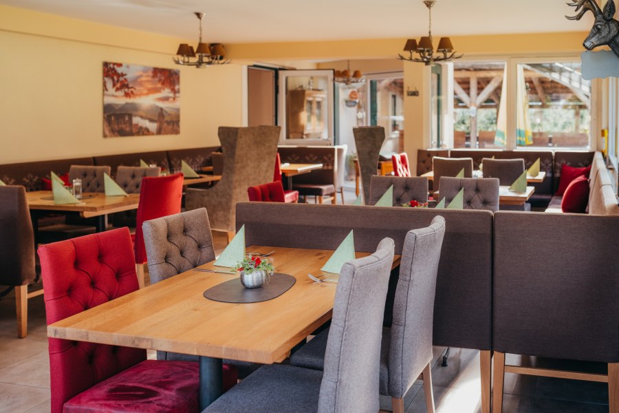 Gem&uuml;tliches Restaurant mit Holztischen und gepolsterten St&uuml;hlen.