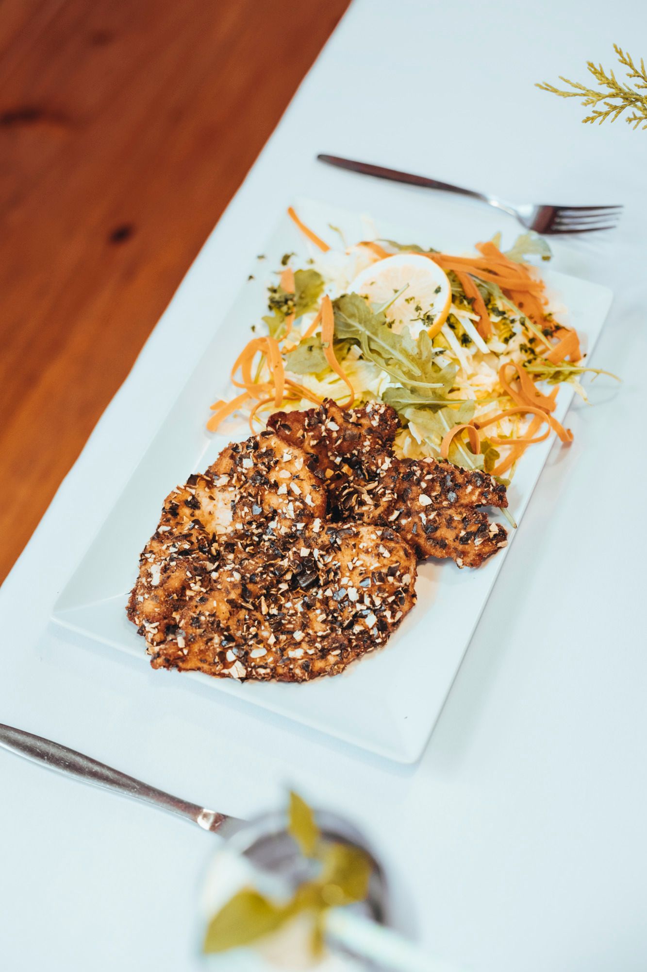Hühnerschnitzel mit Kürbiskernpanade und Salat auf einem weißen Teller.