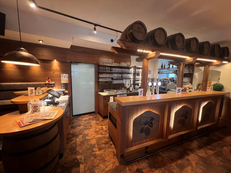 Rustikale Bar mit Holzverkleidung und Bierfässern als Dekoration.
