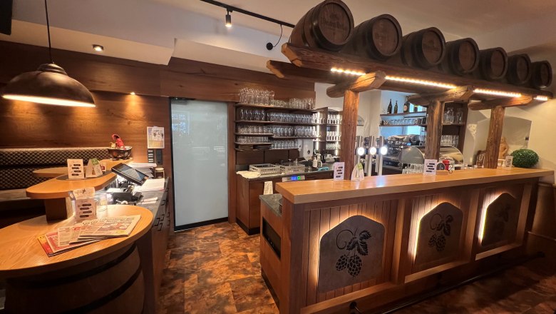 Rustikale Bar mit Holzverkleidung und Bierfässern als Dekoration.
