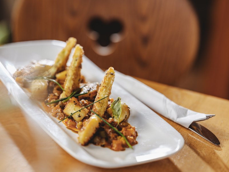 Gourmetgericht auf wei&szlig;em Teller mit frittierten Gem&uuml;sesticks und Kr&auml;utern.
