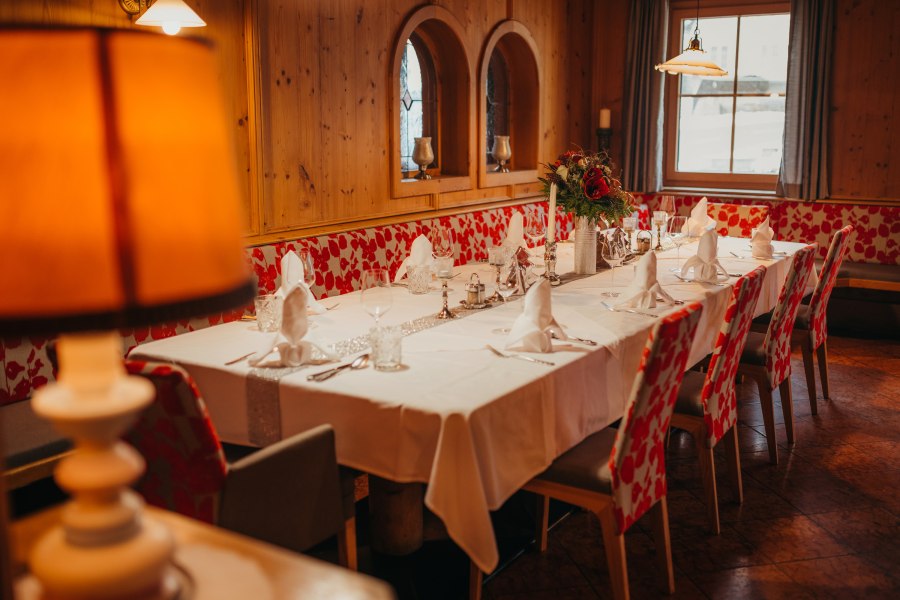 Elegantes Gastzimmer mit gedecktem Tisch, Holzverkleidung und Blumenarrangement.