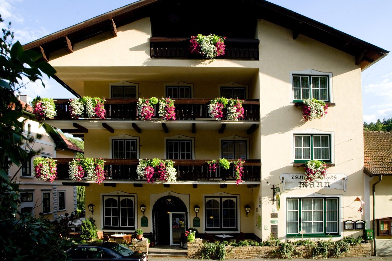 Fassade eines traditionellen Gasthauses mit Balkonen voller Blumen.