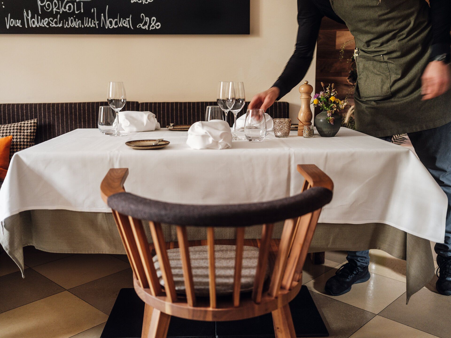 Gastwirtschaft Floh in Langenlebarn, ein Kellner deckt den Tisch ein, weißes Tischtuch, alte Holzmöbel, weiße Stoffservietten, Gedeck.