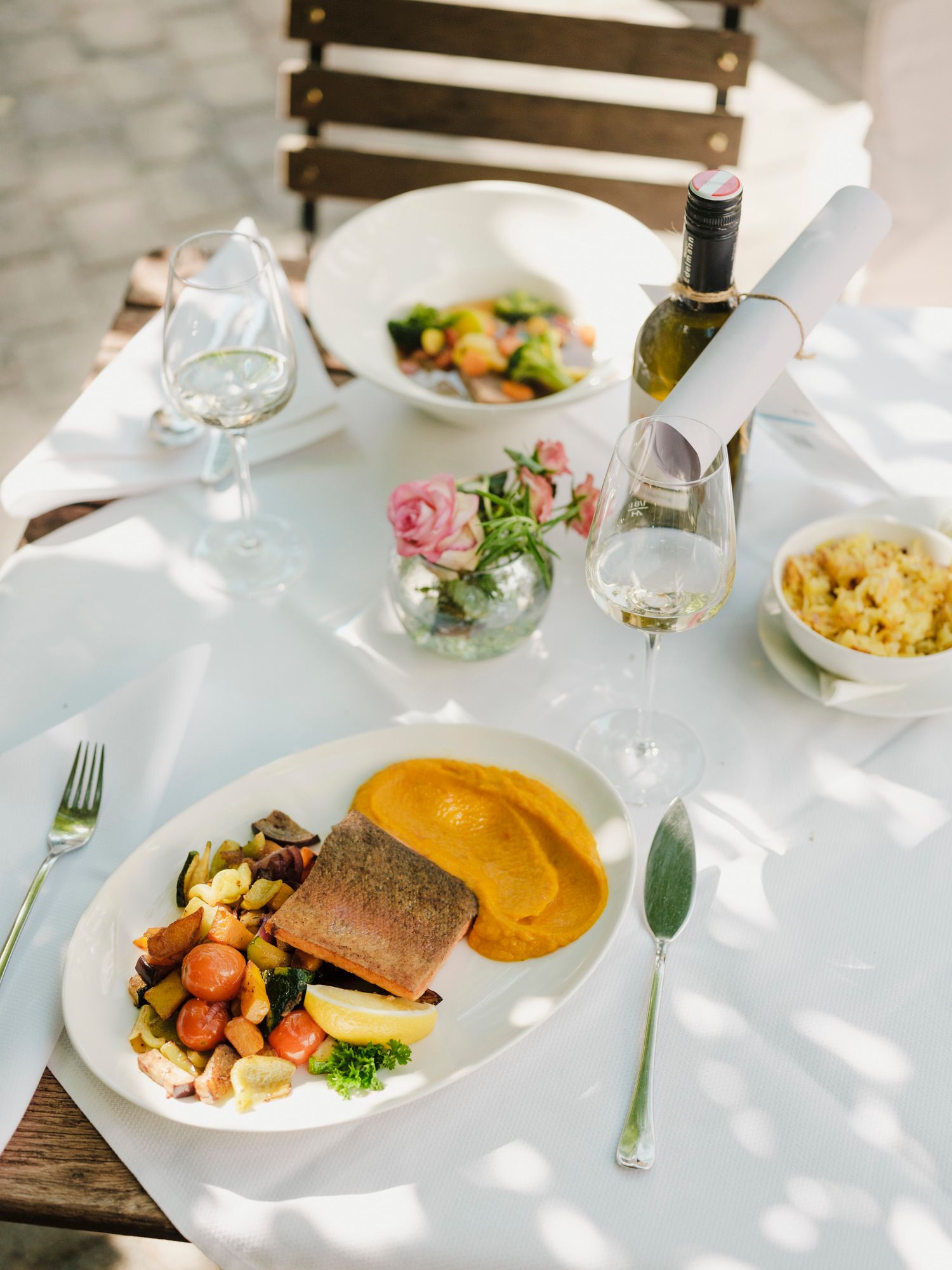 Elegant outdoor lunch with fish, vegetables and white wine.