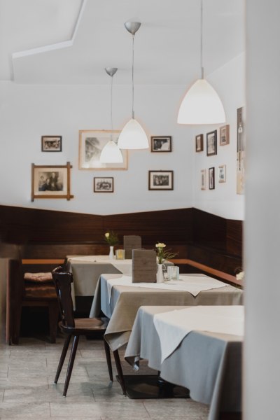 Gem&uuml;tliches Caf&eacute; mit Holzm&ouml;beln, Tischdecken und Wandbildern.