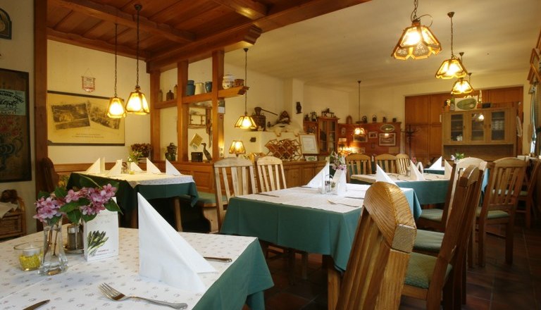 Innenansicht eines gemütlichen Wirtshauses mit Holzmöbeln und gedeckten Tischen.