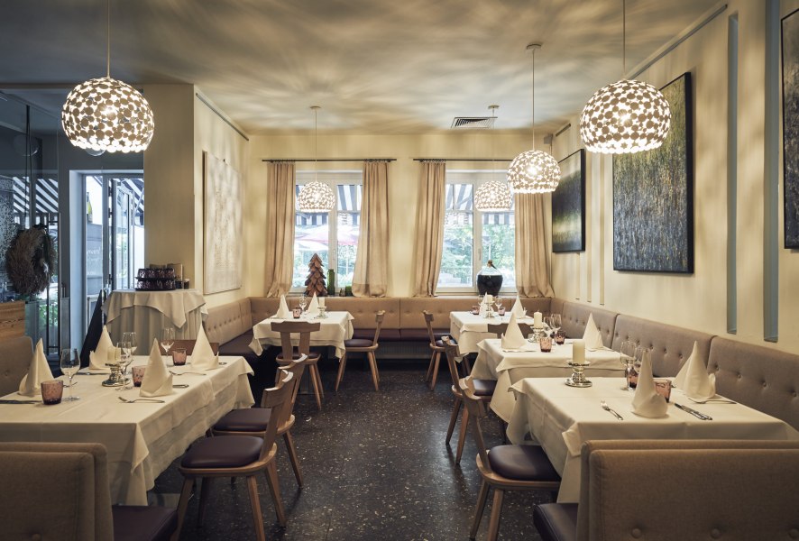 Elegantes Restaurant mit gedeckten Tischen, modernen Lampen und Kunst an den Wänden.