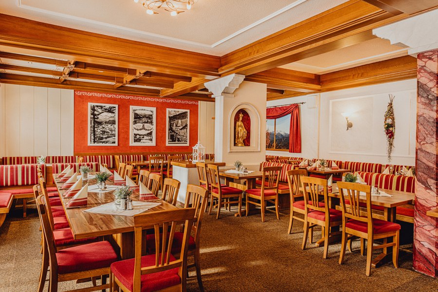 Gem&uuml;tlicher Gastraum mit Holzm&ouml;beln und rot-wei&szlig; gestreiften Polstern.