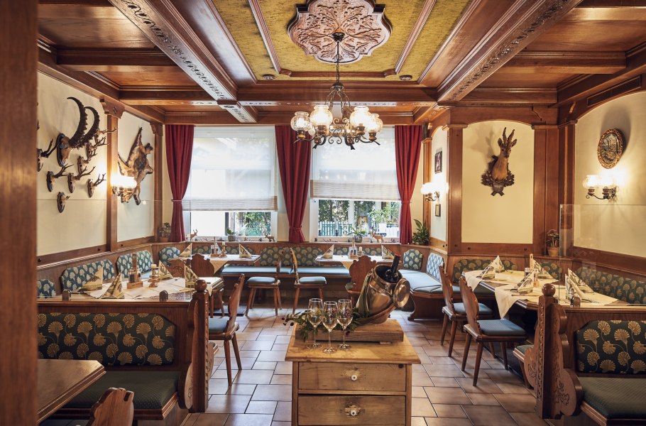 Gemütliche Jägerstube mit Holzmöbeln, Jagdtrophäen an den Wänden und gedeckten Tischen.