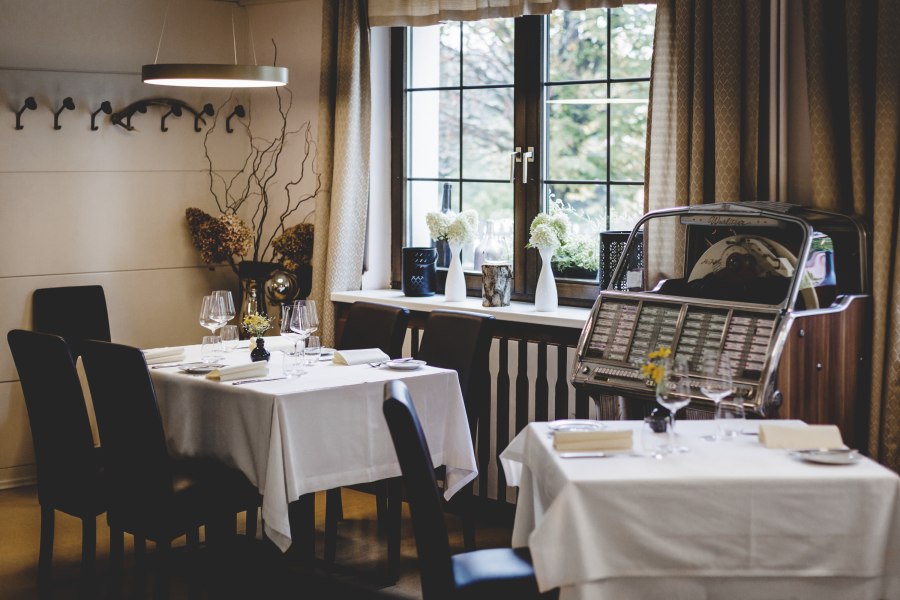Gem&uuml;tliches Restaurant mit gedeckten Tischen und Jukebox am Fenster.