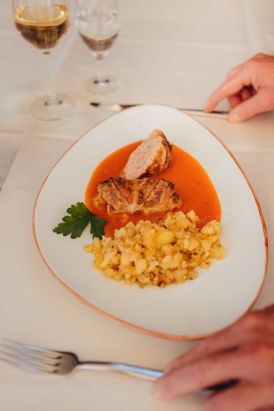 Krautroulade mit Kartoffeln und Soße auf weißem Teller serviert.