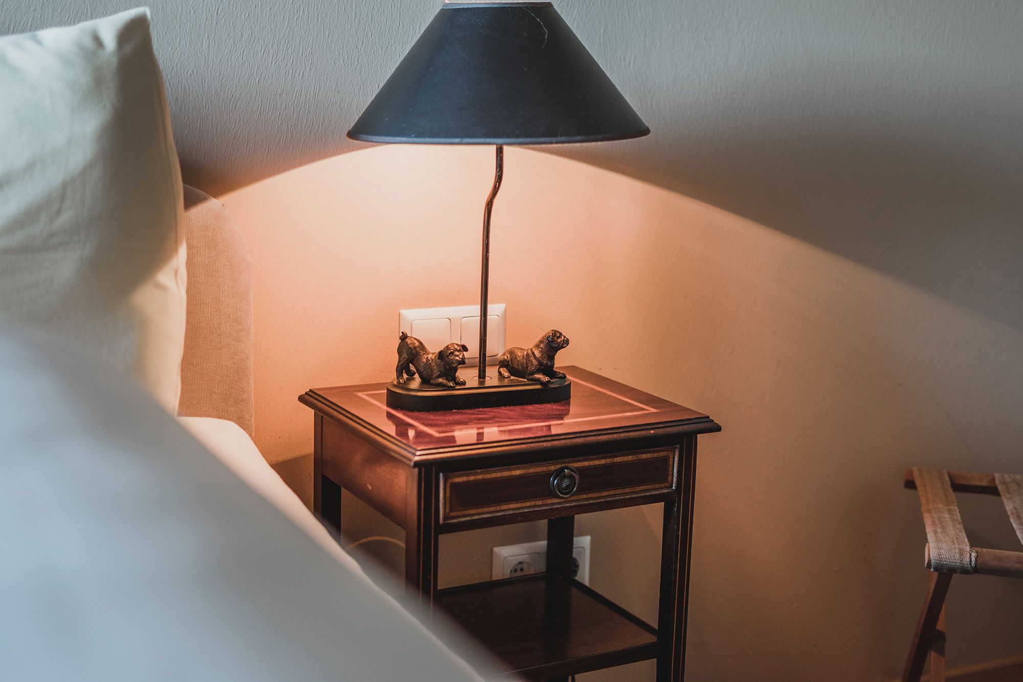 Nachttisch mit Lampe und Hundeskulpturen in einem Doppelzimmer.