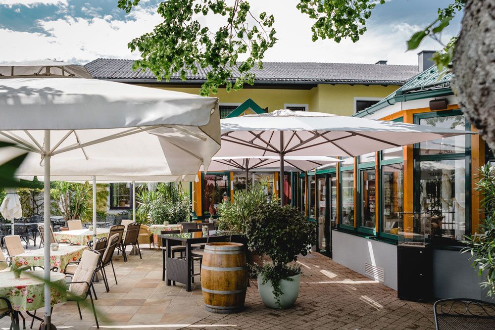 Außenbereich eines Restaurants mit Tischen, Stühlen und Sonnenschirmen.