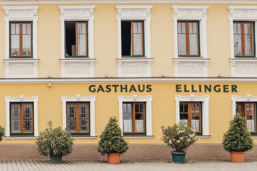 Fassade eines gelben Gasthauses mit der Aufschrift 'Gasthaus Ellinger'.